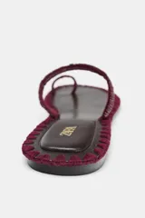 Sandalia plana con tira para el dedo y tira en el empeine con detalle de abalorios. Suela con pespuntes a contraste de color y acabado en punta redonda.