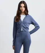 Campera corta azul acero con capucha, mangas largas y cierre frontal de cremallera metálica doble.