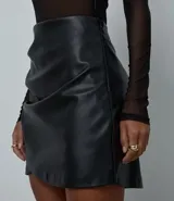 Pollera corta de material sintético tipo cuero (PU), con diseño texturizado y detalle de fruncido lateral.