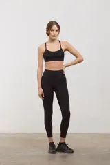 Top deportivo negro de compresión media, con escote redondo clásico, tiras finas cruzadas en la espalda y tazas intercambiables.