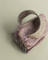 Brazalete rígido de diseño artesanal con textura irregular y acabado metálico, elaborado en bronce macizo.