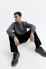 Buzo de algodón color crema, corte oversize, con escote redondo y puños. Presenta un estampado gráfico grande en la espalda con un globo aerostático y texto que incluye "SOME PEOPLE MIGHT THINK I'M WEIRD BUT, I DON'T CARE" y otros símbolos gráficos.