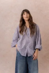Camisa lila oversize de algodón con bordado floral calado tipo broderie, cuello camisero, manga larga y abotonadura frontal.