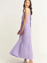 Vestido largo lila con volados en diferentes tamaños, escote cuadrado y lazos en la espalda.