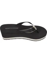 Ojotas de mujer con plataforma tipo cuña de color negro. Las tiras son de textil negro con una banda central que lleva el texto "HILFIGER" en dorado y el logo de Tommy Hilfiger en la unión con la base.