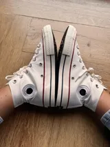 Zapatillas de lona color beige, tipo bota, con cordones marrones, puntera de goma y logo de peach engomado.