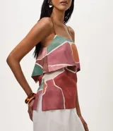 Blusa de breteles finos confeccionada en viscosa, con diseño de superposición en el busto y estampado geométrico multicolor en tonos terracota, verde y beige.