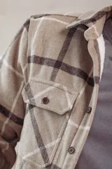 Sobrecamisa de corte holgado con diseño a cuadros en tonos azul marino y marrón, confeccionada con forro interior de corderito sintético, cuello clásico, cierre frontal de botones y bolsillos en el pecho.