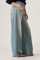 Jeans de corte recto y tiro alto, con diseño de pierna ancha y acabado lavado en tono celeste claro. Presentan cierre frontal con botón y cremallera, además de bolsillos laterales y traseros.