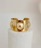 Brazalete rígido dorado con tres esferas grandes.