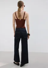 Jeans de corte recto y tiro medio en color azul oscuro, con costuras en contraste y acabado sin rematar en el ruedo.