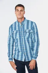 Camisa de manga larga confeccionada en tela de viyela, con estampado de cuadros en tonos azules y líneas claras. Presenta cuello clásico, cierre frontal con botones y dos bolsillos en el pecho con solapa y botón.