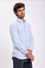 Camisa de vestir celeste con rayas verticales blancas, de corte clásico, manga larga con puños abotonados y bolsillo en el pecho.