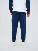 Pantalón deportivo azul marino con puños elásticos en los tobillos, bolsillos laterales con cierre, escudo del Club Nacional de Football en una pierna y logo de Umbro en la otra.