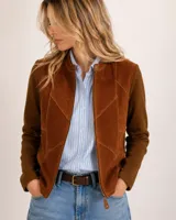Campera de mujer combinada en lana merino y gamuza, color marrón. Presenta diseño tipo patch en el frente con paneles de gamuza con costuras visibles a contratono, cuello mao con cierre de botón a presión, mangas largas de punto acanalado y cierre frontal con cremallera.