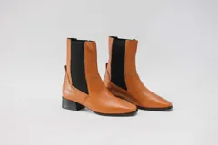 Botas de cuero color beige con elásticos laterales negros, taco cuadrado y punta cuadrada.