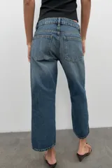 Jeans de tiro bajo con corte wide leg y largo cropped. Presenta diseño de cinco bolsillos, trabillas para cinturón y cierre frontal con cremallera y botón metálico.