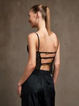 Top negro con breteles finos, escote en V y cuerpo de encaje con diseño geométrico.