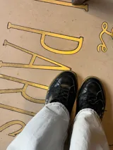 Championes negros de cuero con apliques metálicos plateados y suela color caramelo.