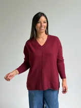 Sweater de punto color bordó, con escote en V, manga larga y costura central vertical decorativa.