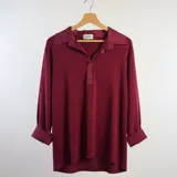 Chomba de algodón color bordó, con cuello camisero y cierre frontal parcial. Presenta mangas largas con puños anchos y un diseño holgado.