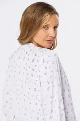 Blusa de manga larga blanca con estampado floral en negro, cuello redondo y cierre frontal con botones.