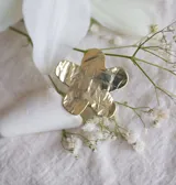 Anillo dorado con forma de flor de hibisco con textura arrugada.