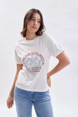Remera básica de manga corta color crudo con estampa frontal circular que incluye flores en tonos celestes y la inscripción en color bordó "L'Atelier Botanique Fleurs La beauté de la nature".