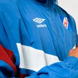 Buzo deportivo Umbro del Club Nacional de Football, con medio cierre frontal, cuello alto y diseño en bloques de color azul, blanco y bordó. Presenta el logo de la marca y el escudo del club en el pecho.