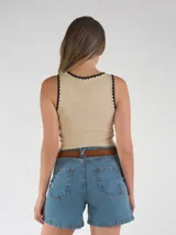Musculosa marrón oscura, al cuerpo, sin mangas, con ribetes en contraste de color beige y negro en el escote y las sisas.