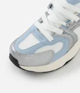 Championes de estilo urbano Satinato, confeccionados en poliuretano con diseño de recortes superpuestos en tonos celeste, blanco y plateado metalizado. Cuentan con cordones blancos, forro acolchonado y una suela robusta y texturizada en tono crudo y celeste.