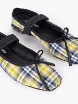 Ballerina de diseño escocés en tonos verde, amarillo y azul, con ribetes en cuero negro. Presenta una banda elástica sobre el empeine, un pequeño lazo decorativo en la punta y un taco bajo con incrustaciones de cristales.