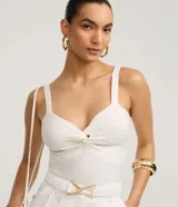 Blusa cropped de tiras anchas en tejido de punto texturizado, color blanco, con escote en V y nudo torcido en el busto.