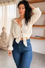Camisa de algodón color beige, de manga larga y diseño holgado, con cierre frontal de botones y cuello camisero.