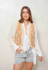 Chaleco de denim color camel con bordados florales en blanco y aplicaciones de perlas en el frente.