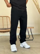Pantalón jean de corte recto y holgado, color negro, con diseño de cinco bolsillos y cierre frontal con botón y cremallera.