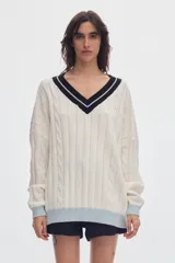 Sweater de punto oversized de color marrón, con escote en V, detalles de ochos y puños, cuello y ruedo en tono celeste y blanco.