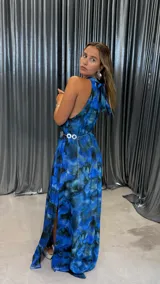 Vestido largo azul con estampado abstracto, cuello halter y espalda descubierta. Incluye cinturón plateado con eslabones circulares.