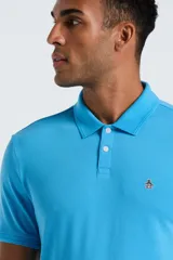 Chomba de piqué color celeste, con cuello clásico, cierre frontal de dos botones y logo bordado en el pecho.