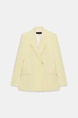 Blazer de corte cruzado color amarillo pastel, con cuello de solapa, manga larga, bolsillos delanteros con solapa y cierre frontal con botones forrados.