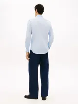 Camisa celeste de corte slim, confeccionada en sarga de mezcla de algodón elástico. Cuenta con cuello italiano, manga larga con puños y cierre frontal con botones.
