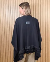 Ruana tejida de algodón en color negro, con diseño amplio y volados en el borde inferior.