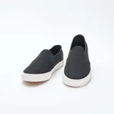 Zapatillas bajas slip-on negras de malla con suela blanca.