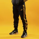 Pantalón de jogging Puma King, color negro con detalles y franjas laterales amarillas con diseño estampado, y logo Puma King bordado.