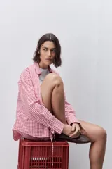 Camisa de calce relajado y silueta amplia con estampado cuadrillé en tonos rojo y blanco. Presenta cuello clásico, cierre frontal mediante botones y mangas largas.