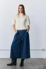 Jeans de tiro medio con diseño culotte y pierna ancha. Presenta cinco bolsillos, detalle de pinzas en el delantero y cierre frontal con cremallera y botón metálico.