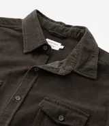 Camisa de hombre color verde oscuro, confeccionada en terciopelo, con cuello clásico, manga larga y dos bolsillos frontales con solapa y botón. Cierre frontal con botones.