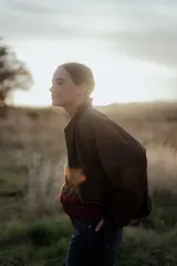 Campera tipo bomber color marrón oscuro, con cierre frontal, cuello redondo y diseño holgado.