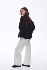 Campera de corte holgado confeccionada en sherpa suave, con escote redondo y cierre frontal de botones. Presenta hombros caídos, ribetes en tejido revestido y bolsillos laterales discretos.