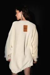 Sweater oversized color crema, tejido de punto con escote en V, roturas en ruedo y puños, y badana de PU en la espalda.